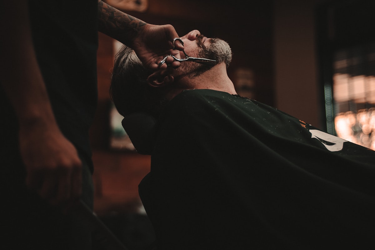 Barber trimming a client's beard inside a real barbershop