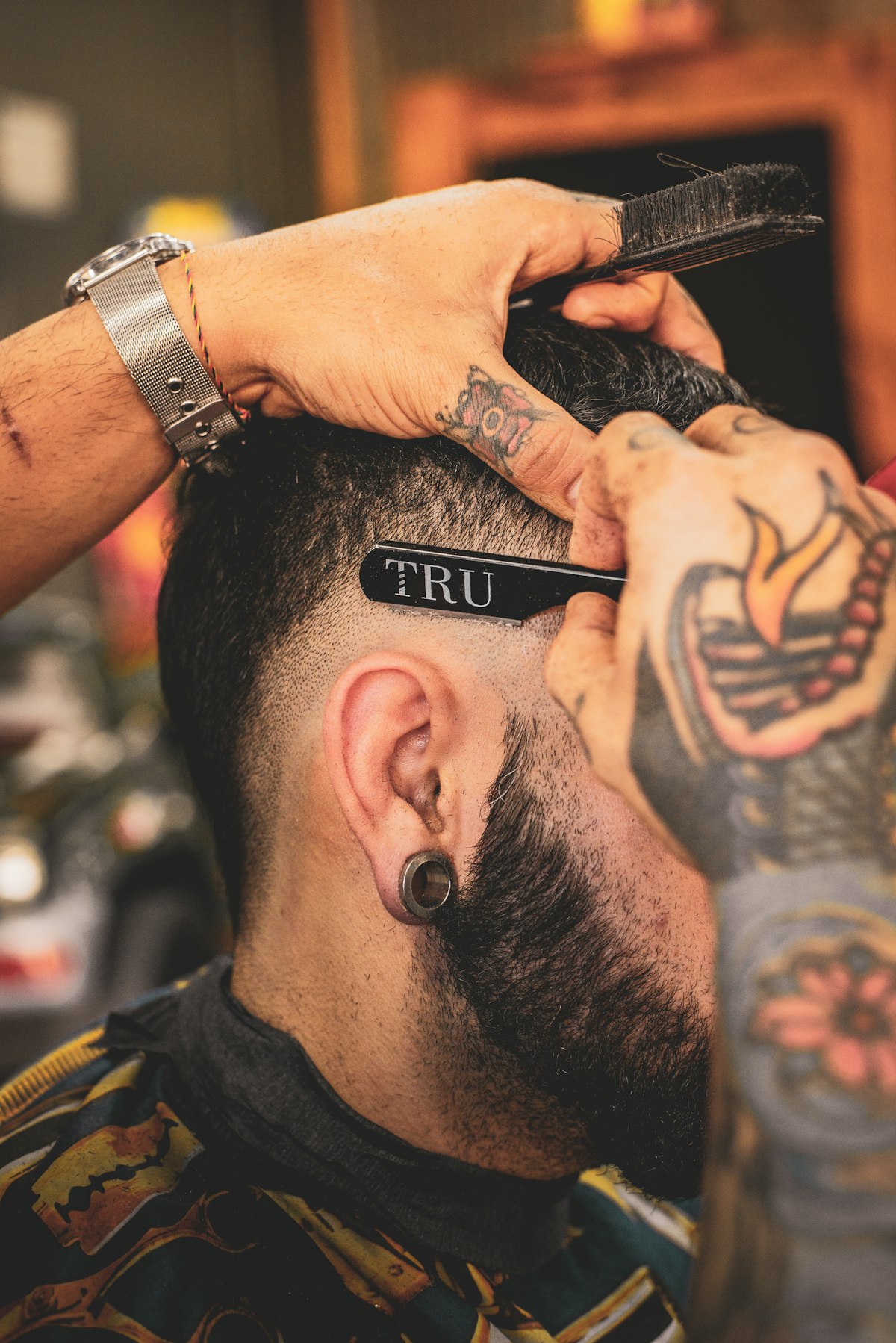 Barber detailing a mid fade haircut with a straight razor